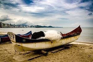 Bateaux de pêche avec des filets de pêche sur la plage d'Itajai sous un ciel nuageux au Brésil. sur Dieter Walther