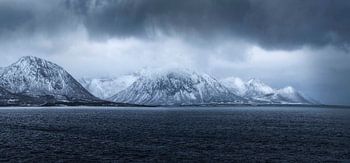 Die schneebedeckten Berge umrahmen das ruhige Wasser des Fiskebol auf den Lofoten, 