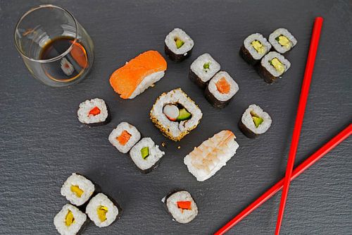 Sushi op zwart serveerbord geserveerd met rode eetstokjes