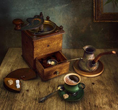 Still life with a cup of hot coffee and an old coffee grinder.