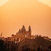 Kerk en vulkaan met wolken tijdens de warme, oranje, zonsopkomst in Mexico van Maartje Hensen