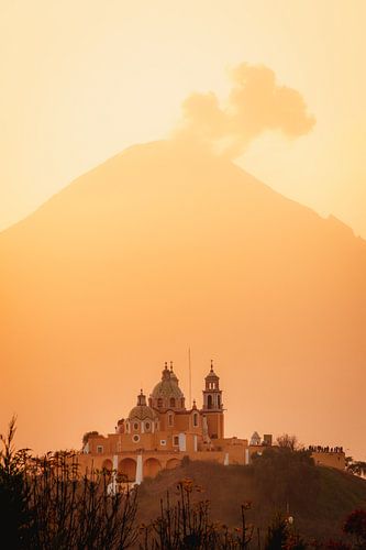 Kerk en vulkaan met wolken tijdens de warme, oranje, zonsopkomst in Mexico