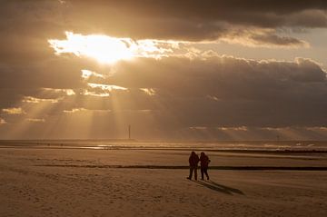 Couple walking in Bredene by the sea by Nicola Mathu