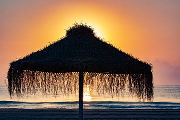 Parasol sur la plage au coucher du soleil