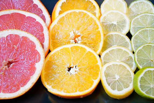 Citrusvruchten in plakjes gesneden en op een zwarte serveerplank gelegd