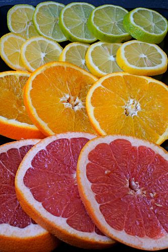 Citrusvruchten in plakjes gesneden en op een zwarte serveerplank gelegd