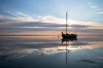 Voilier séché dans un vaste paysage des Wadden au coucher du soleil