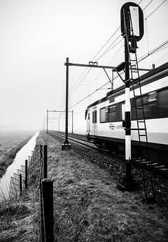 Ein typischer Niederländischer Zug kommt aus dem Nebel und passiert ein Eisenbahnsignal.