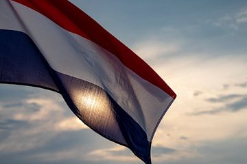 Nederlandse vlag tegen een ondergaande zon. van Femke Ketelaar