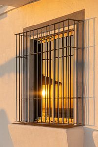 Sonnenuntergang spiegeln sich in einem Fenster einer weißen Fassade. Rota, Costa de la Lutz, Cádiz, Andalusien, Spanien.