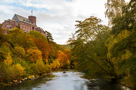 The River Rur in autumn, with Hengebach Castle on the hill in Heimbach