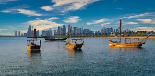 Doha skyline vanaf de corniche promenade middag shot met dhows met Qatar vlag in de Arabische golf o