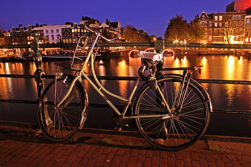 Oude fiets aan de Amstel in Amsterdam bij avond van Eye on You