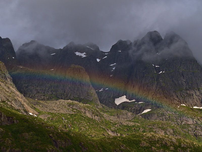 Colorful rainbow in front of rugged mountains in Lofoten, Norway by Timon Schneider