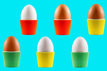 Coloured vintage egg cups with eggs on a blue background by Peter de Kievith Fotografie