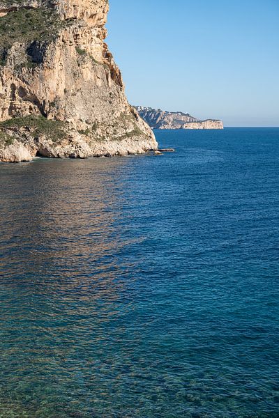 Cliffs and reflections in clear seawater by Adriana Mueller