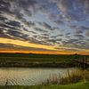 Bruggetje over het kanaal, met zon opkomst. van Henk Cruiming