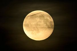 Full moon shining bright in dark night, amber moon with some few puffy, hazy clouds and a plane / an by wunderbare Erde