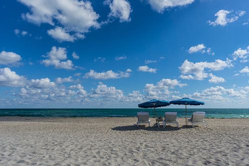 Verenigde Staten, Florida, Leeg strand van Miami met twee blauwe parasols en drie ligstoelen