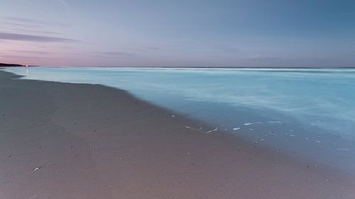 Strand en lichtblauwe zee onder een paarse hemel