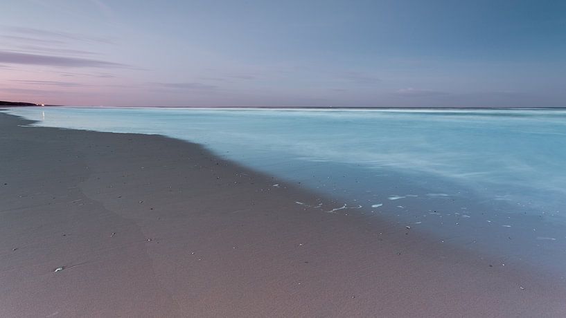 Strand en lichtblauwe zee onder een paarse hemel von Remco Bosshard