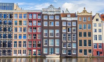 Een bootje ligt voor de historische grachtenpanden aan het Damrak in Amsterdam, Nederland