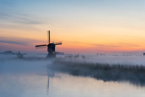 Atmosphärischer Sonnenaufgang mit Mühle und tief hängendem Nebel