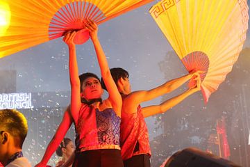 Artiste de danse levant les bras avec des éventails en papier lors d'un festival culturel sur kall3bu