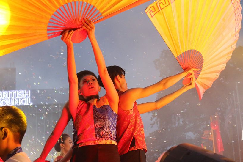 Dance artist raising arms with paper fans at a cultural festival by kall3bu