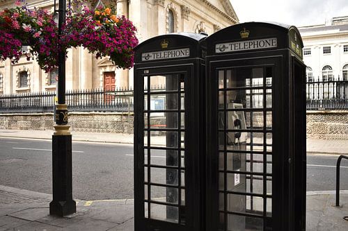 Black phone booths London next to hanging flowers