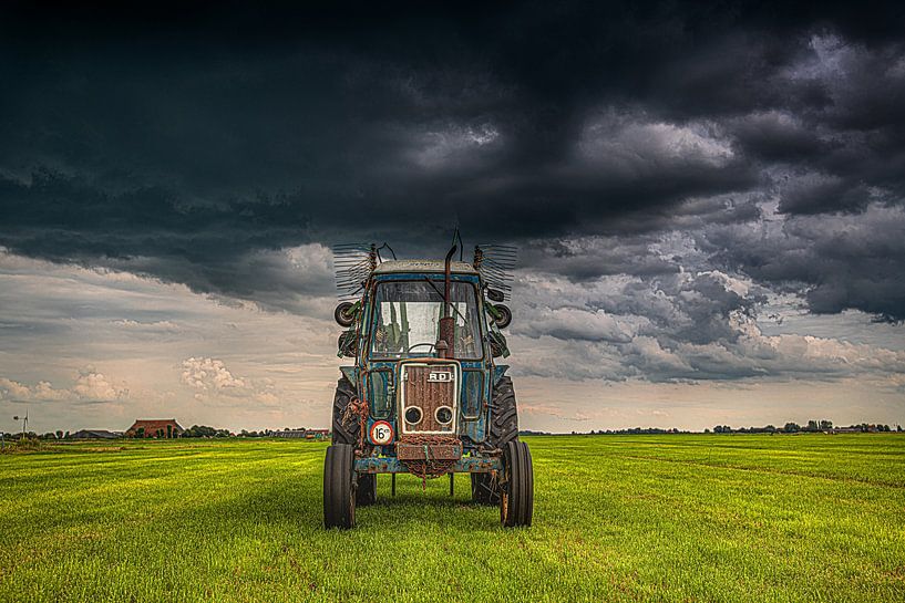 Tracteur dans la campagne frisonne sous un ciel lourd et nuageux. par Harrie Muis