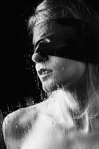 Mooie vrouw achter glas met een blinddoek voor haar ogen.