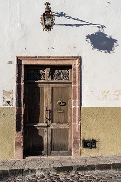 Oude houten deur in het avondlicht in een straat in Mexico van Sandra Schmidt