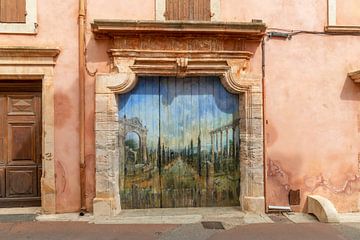 Roze muur mer gedecoreerde deur in dorpje Loumarin, Frankrijk van Joost Adriaanse