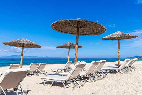 Sun loungers and thatched roofs on Kassandra beach, Greece