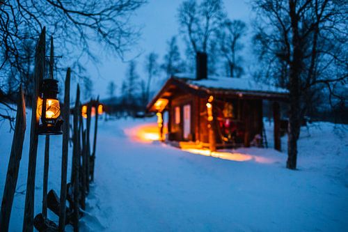 Illuminated wooden hut in winter landscape