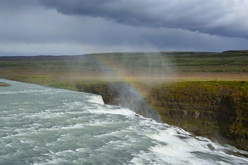 Een regenboog onder donkere wolken