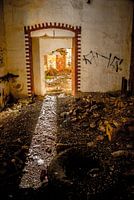 Tür in verfallenem Gebäude mit Sonnenlicht.