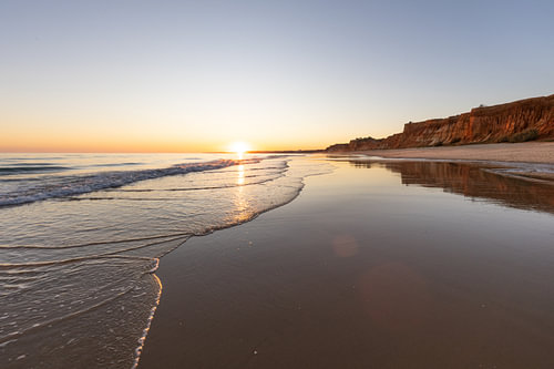 Zonsondergang op het zandstrand Praia da Falésia. Kliffen Roze bloemen bij Albufeira, Portugal