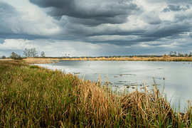 A dramatic Dutch sky with clouds over a water-rich marshland landscape by Fotografiecor .nl