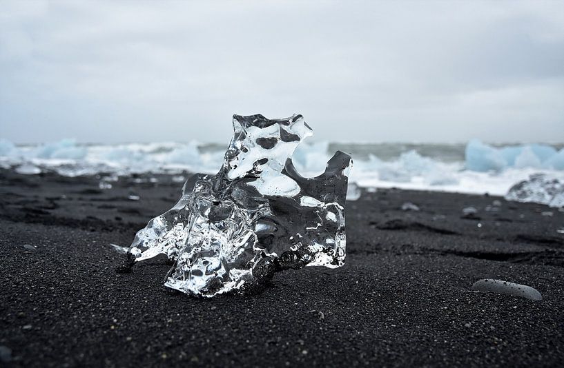 Kristalhelder ijsrots op zwarte sand bij ijsmeer Jokulsarlon, Ijsland van Jutta Klassen