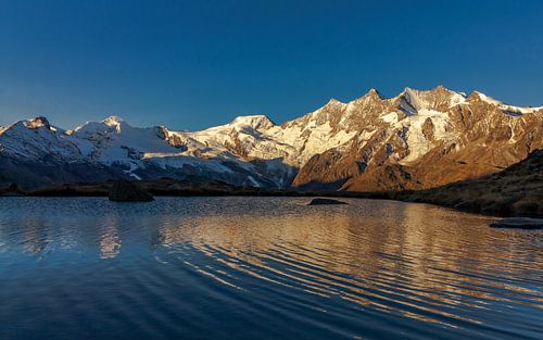 Sunrise on mountain peaks of Saas-Fee at mountain lake