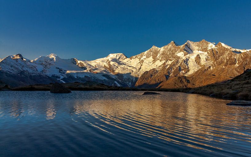 Sunrise on mountain peaks of Saas-Fee at mountain lake by Maarten Salverda