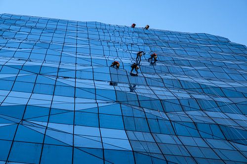 Glazenwassers op eenzame hoogte op glazen gevel