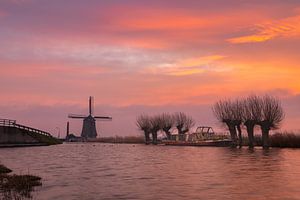 Le moulin Kaag, des saules têtards et un bateau à Spanbroek (Hollande septentrionale) sous un ciel aux couleurs vives.