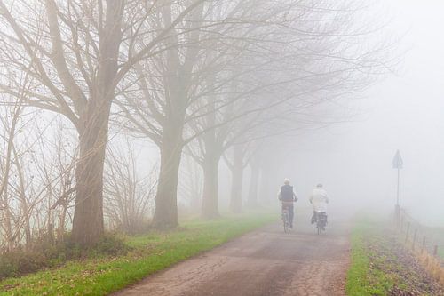 Mistig landschap met twee fietsers van Chris Stenger