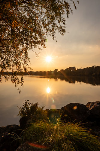 Romantischer Sonnenuntergang an idyllischem See mit Sonnenschein und Spiegelung