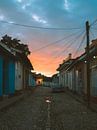 Oranje zonsopkomst in een straat in Trinidad de Cuba met oldtimer en kater van Michiel Dros thumbnail