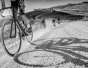 Schwarz-weißes Kunstfoto von Radfahrern, die auf den legendären Schotterstraßen Strade Bianche in der Toskana, Italien, fahren
