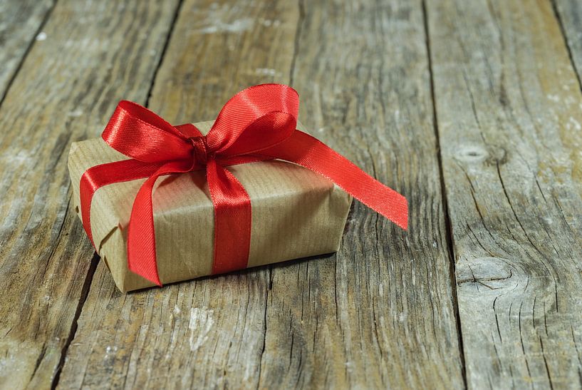 Enkele geschenkdoos met strik van rood lint op hout van Alex Winter